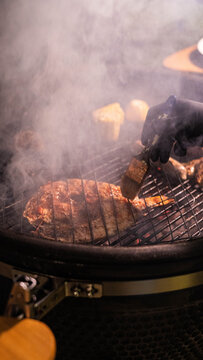 Gourmet meat cuts grilling on a barbecue pit with smoke rising in an atmospheric outdoor kitchen