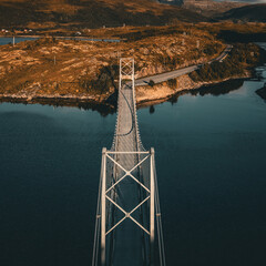 Vertical aerial view of a symmetrical suspension bridge crossing a fjord towards autumnal mountains in Norway with copy space © Quality by Simon