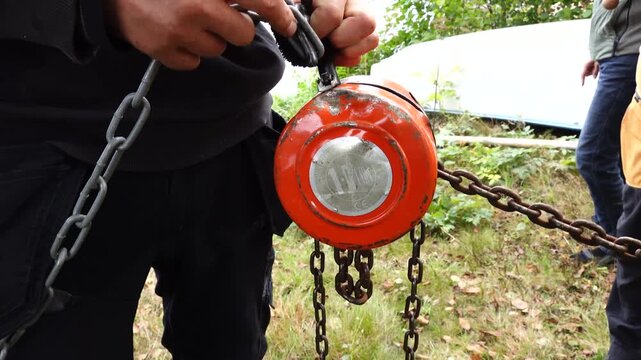 Stockholm, Sweden. A man's hands hold a manual hand-chain hoist (lifting block) in a yard. 