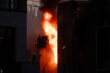 Obraz premium Firefighters put out the burning building of the shopping center. Smoke and fire after a drone attack in Ukraine, rescuers are working at the scene