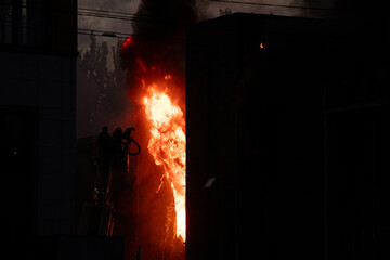 Obraz premium Firefighters put out the burning building of the shopping center. Smoke and fire after a drone attack in Ukraine, rescuers are working at the scene