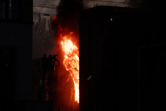 Firefighters put out the burning building of the shopping center. Smoke and fire after a drone attack in Ukraine, rescuers are working at the scene