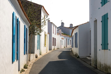 Ruelle pittoresque et maisons blanches traditionnelles aux volets colorés dans le village de Saint-Sauveur, Île d'Yeu, France. © skerdreux