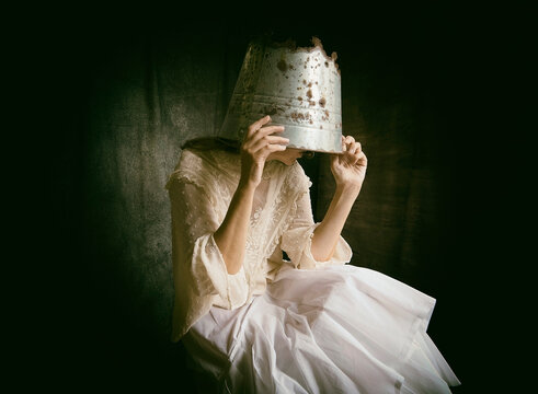 Romantic portrait of a woman with a rusty metal bucket covering her head III