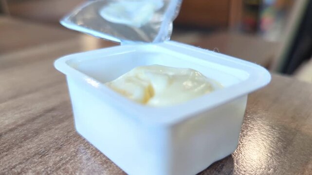 Rustic potato wedges dipped in sauce served in a single-use plastic container. Highlights fast food convenience but draws attention to excessive consumption and plastic waste issues.