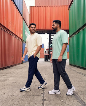 Two young men walking together wearing blank oversized t-shirts in cargo container yard streetwear mockup Generative Ai