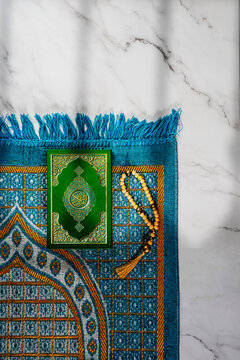 Book with Arabic title All Quran, religious scripture.  Prayer Mat Islamic rug for Namaz, muslim prayer beads for Salat .