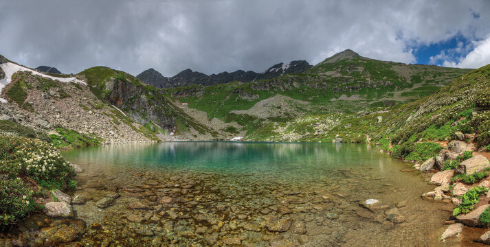 A high-mountain lake with rhododendrons blooming along its shores.