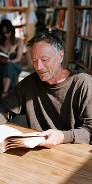 Older man reading an open book in a cozy library with natural light for portrait background and lifestyle website use