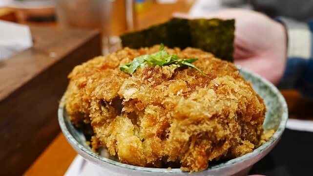 Thick cut of fried pork tonkatsu with crispy golden breadcrumbs placed in a bowl with japanese side dishes for a traditional meal