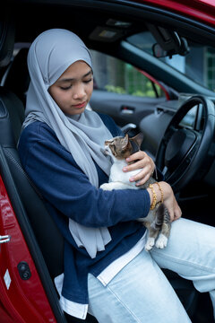 Young woman sitting on a car with cat