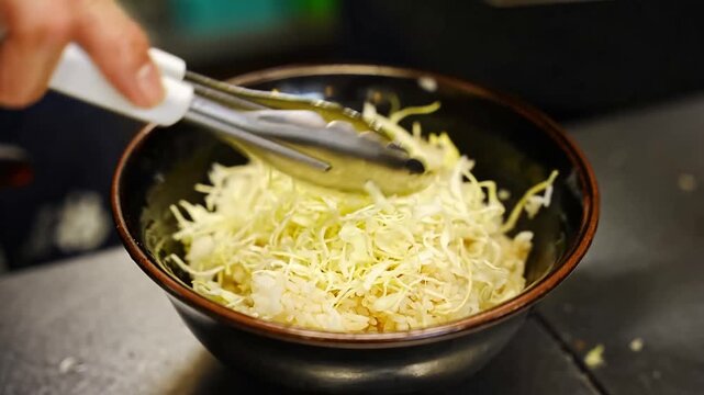 A culinary process involving the slicing of crispy fried pork cutlets on a cutting board, arranging them over shredded cabbage in a bowl with a poached egg, and drizzling savory dark sauce