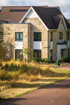 Suburban Brick House Beside Tree-Lined Pathway In Early Autumn With Colorful Foliage in England UK