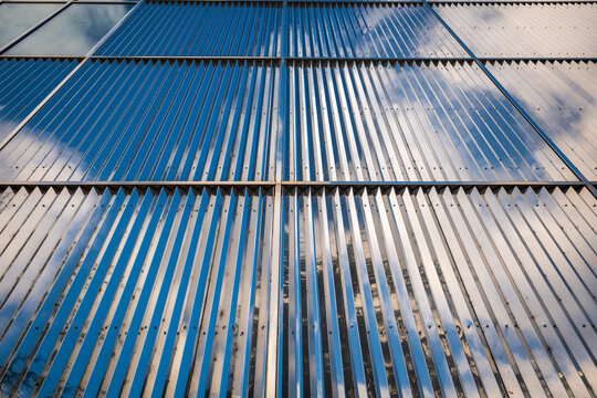 Reflective Corrugated Metal Facade With Sky and Cloud Reflections, Modern Architectural Detail