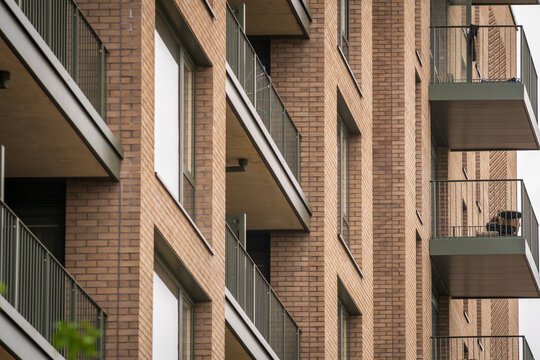 Modern Brick Apartment Building With Balconies Under Overcast Urban Sky in England UK
