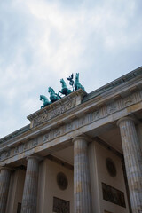 Top part of Brandenburg Gate or Brandenburger Tor monument biggest landmark in Berlin, Germany close up low angle view with grey moody sky background © elifilm