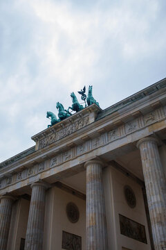 Top part of Brandenburg Gate or Brandenburger Tor monument biggest landmark in Berlin, Germany close up low angle view with grey moody sky background