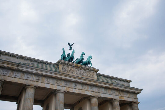 Top part of Brandenburg Gate or Brandenburger Tor monument biggest landmark in Berlin, Germany close up low angle view with grey moody sky background
