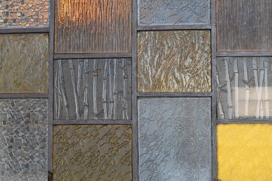 Close-up background composition of assorted textured, patterned, and colored stained glass panels.