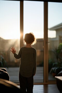 Child silhouette at glass sliding door at sunset for home interior mood and storytelling with warm golden light and calm atmosphere