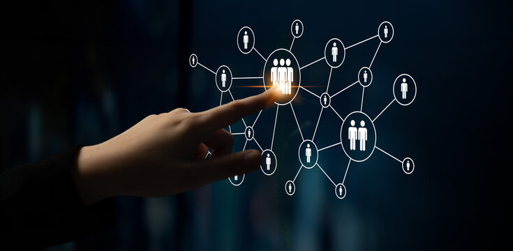 A hand reaches out to select a group of people within a connected digital network, illustrating concepts of interaction, connectivity, and social dynamics in technology. Ledger