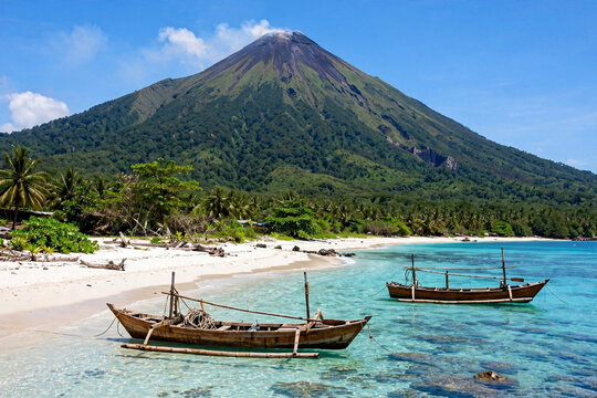 Two traditional outrigger fishing boats on tropical beach with Gamalama volcano mountain in Ternate Maluku Indonesia