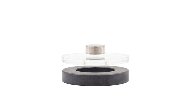 Magnetic levitation experiment with neodymium magnet floating over ferrite ring, physics science demonstration, magnetic repulsion and gravity concept isolated PNG with Transparent Background