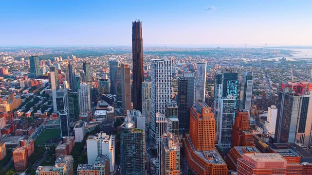 Dense skyscraper skyline of Downtown Brooklyn, New York City, under a clear blue sky. Approaching a dark, neo-Gothic facade of The Brooklyn Tower dominating among the striking skyscrapers.