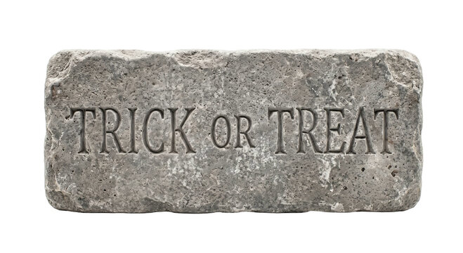 Trick or treat text carved into a rough grey stone block isolated on a white background