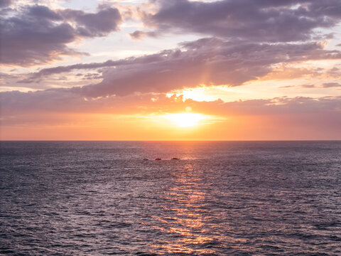 Sunset over the ocean with clouds and waves in the background