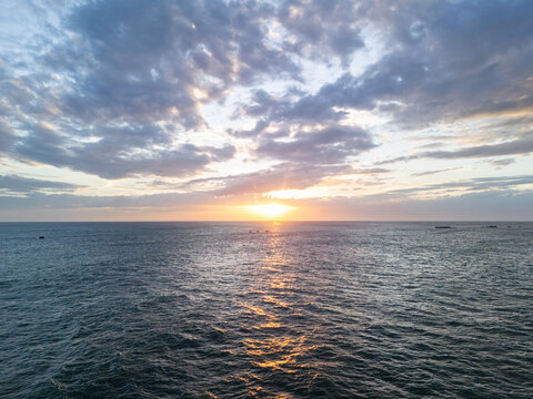 Sunset over the ocean with clouds and gentle waves