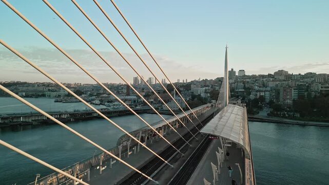 Turkey, Istanbul 06 10 2025: 4K aerial video moving upward over Halic Metro Station on Golden Horn Metro Bridge at early morning sunrise with Sokullu Mehmet Pasha Mosque in background.