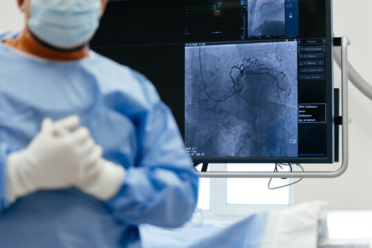 Cardiac catheterization procedure with a medical team observing real-time X-ray imaging of coronary arteries during minimally invasive cardiovascular intervention