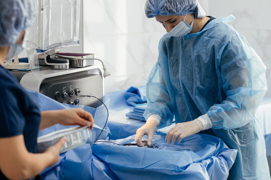 Operating room nurses setting up phacoemulsification machine and sterile instruments before cataract surgery in modern eye clinic