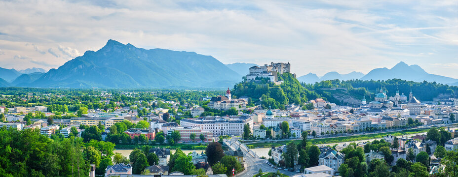 Wide panoramic panorama of Salzburg old town, Austria with Hohensalzburg Fortress, Salzburg Cathedral church, and Alpine mountains