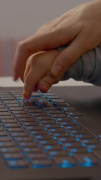 Child and adult typing together on laptop keyboard