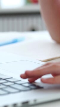 Child uses laptop computer trackpad and keyboard