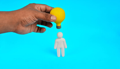 A hand holding a light bulb above a person represents creative thinking and the development of new ideas.  © kaliel