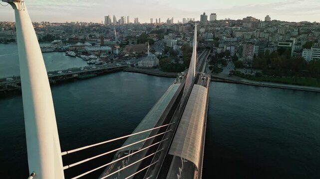 Turkey, Istanbul 06 10 2025: 4K drone video flying backward over Halic Metro Bridge revealing Sokullu Mosque and bridge horns at early sunrise.
