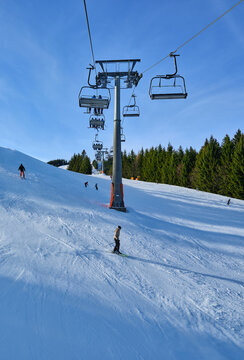 Chairlift and skiers on a sunny piste at Zell am See Austria