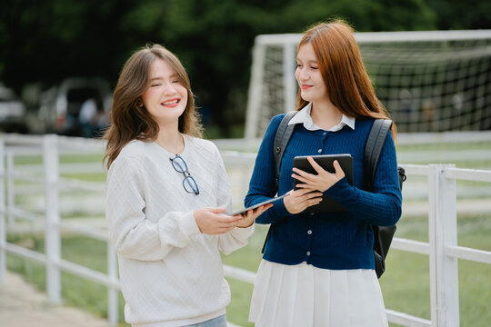 Cheerful students engaging in education and learning together as best friend duos finding joy at school campus with digital tablet