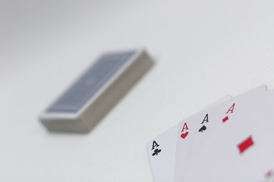 Poker Spielkarten Set mit vier Ass auf weissem Hintergrund und Kartenstapel im Hintergrund