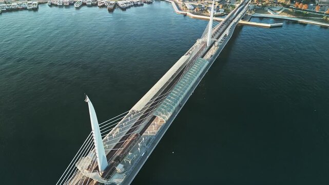 Turkey, Istanbul 06 10 2025: 4K drone video framed diagonally showing Halic Golden Horn Metro Bridge as a metro train arrives at station surrounded by open sea water.
