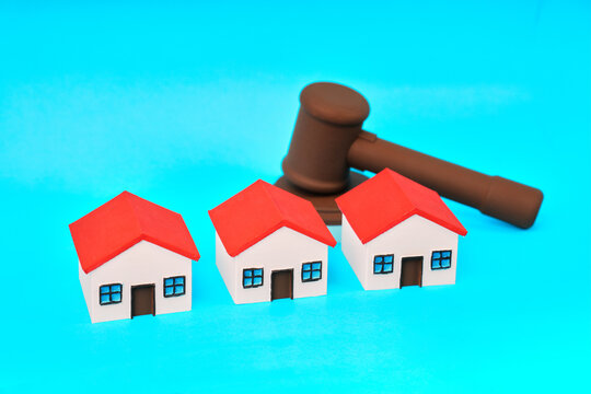 Three miniature houses positioned before a judge gavel represent property law real estate disputes and legal decisions.
