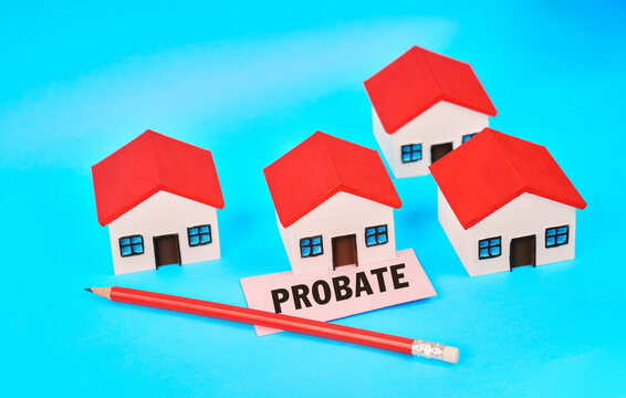 Miniature houses beside a probate sign and pencil representing inheritance, property transfer and estate settlement.
