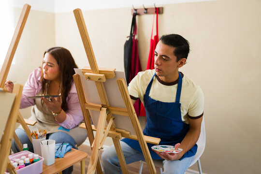 Adults enjoying art class, learning painting on easels, developing creativity and new skills in studio workshop