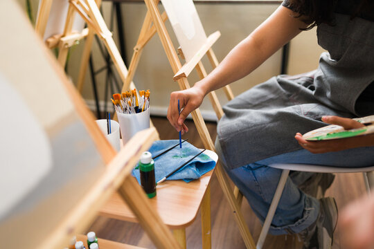 Closeup of artist painting in a workshop using paint brushes and palette, enjoying creative hobby and art class