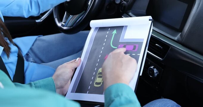 Driving school. Instructor explaining yielding rules to student on scheme in car, closeup