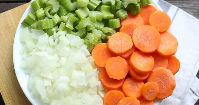 Cut carrots, onions and celery on wooden table, spinning. Top view