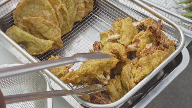 Vendor preparing fried skewers at a street food stall